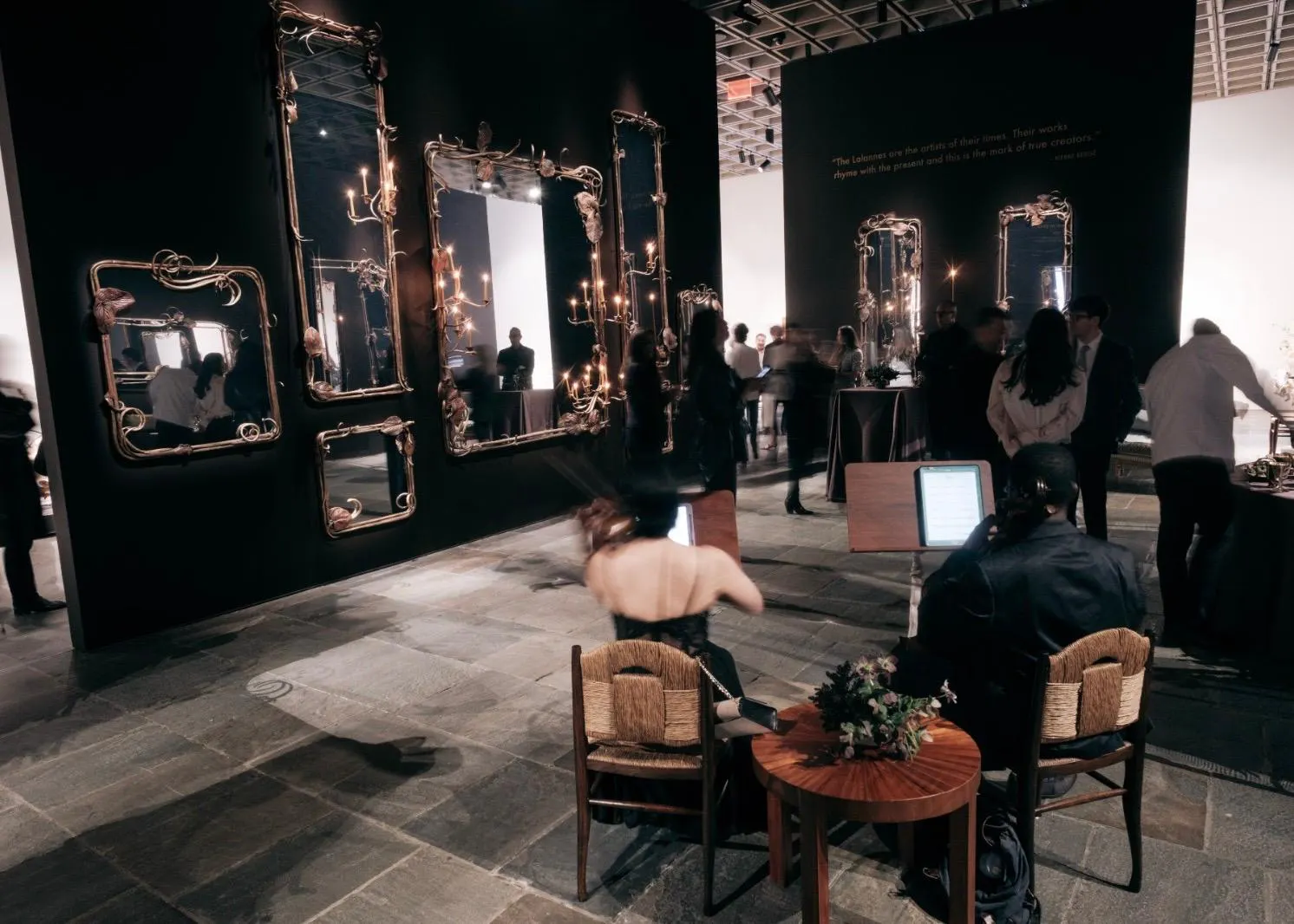 Ausstellung von kunstvollen, vergoldeten Spiegeln von Claude Lalanne an einer schwarzen Wand bei Sotheby's New York, im Vordergrund Musiker.