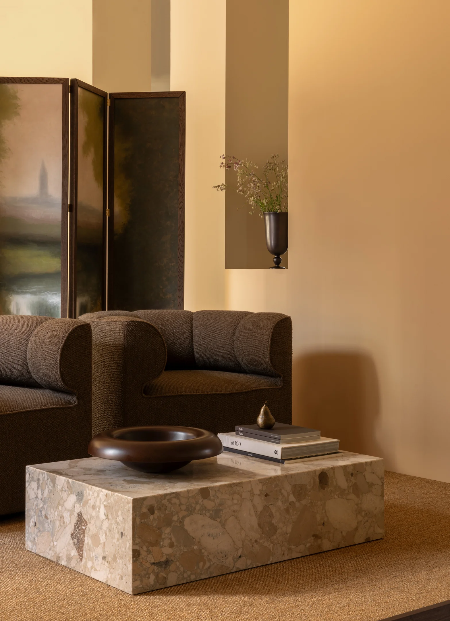 Modernes Wohnzimmer mit Sofa in Braun, Naturstein-Couchtisch, Paravent und warmen Naturtönen.
