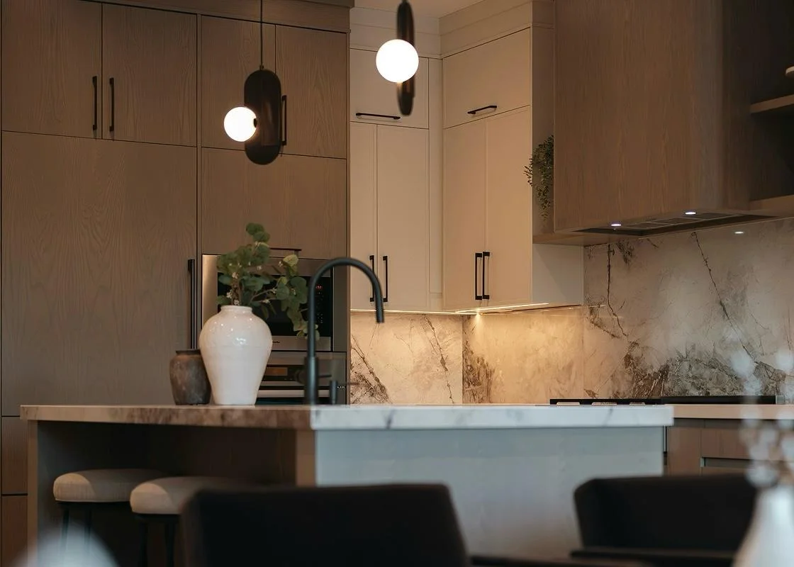 Eine gemütlich beleuchtete, moderne Holzküche mit Kochinsel, Marmor-Rückwand und stilvoller Dekoration, die zu privaten Einladungen nach Hause inspiriert.