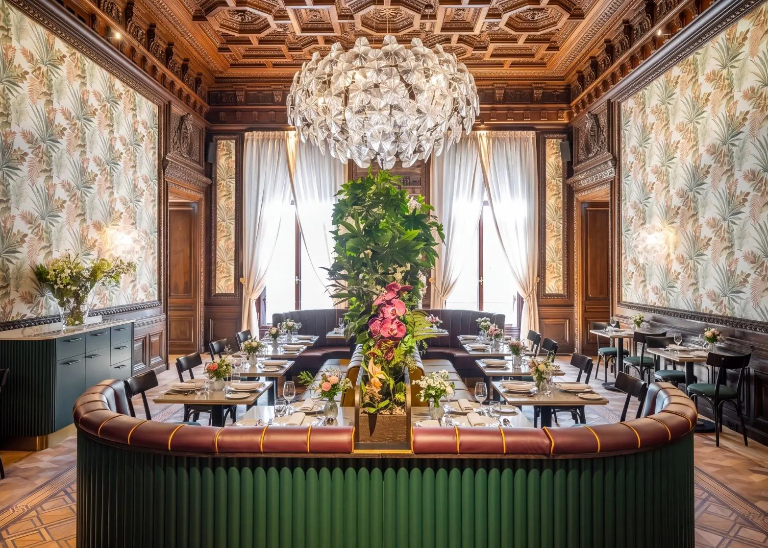 Prachtvoller Frühstückssaal im Hotel Palais Chotek in Wien mit historischer Holzkassettendecke, modernem Pflanzenschmuck und eleganten Sitzgruppen.