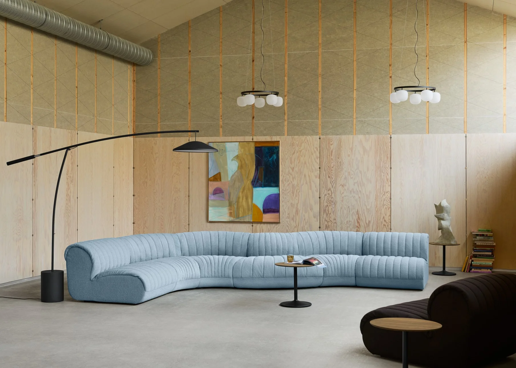 Modernes Wohnzimmer mit hellblauem Sofa, hellen Holzwänden und einer ruhigen, natürlichen Farbpalette.